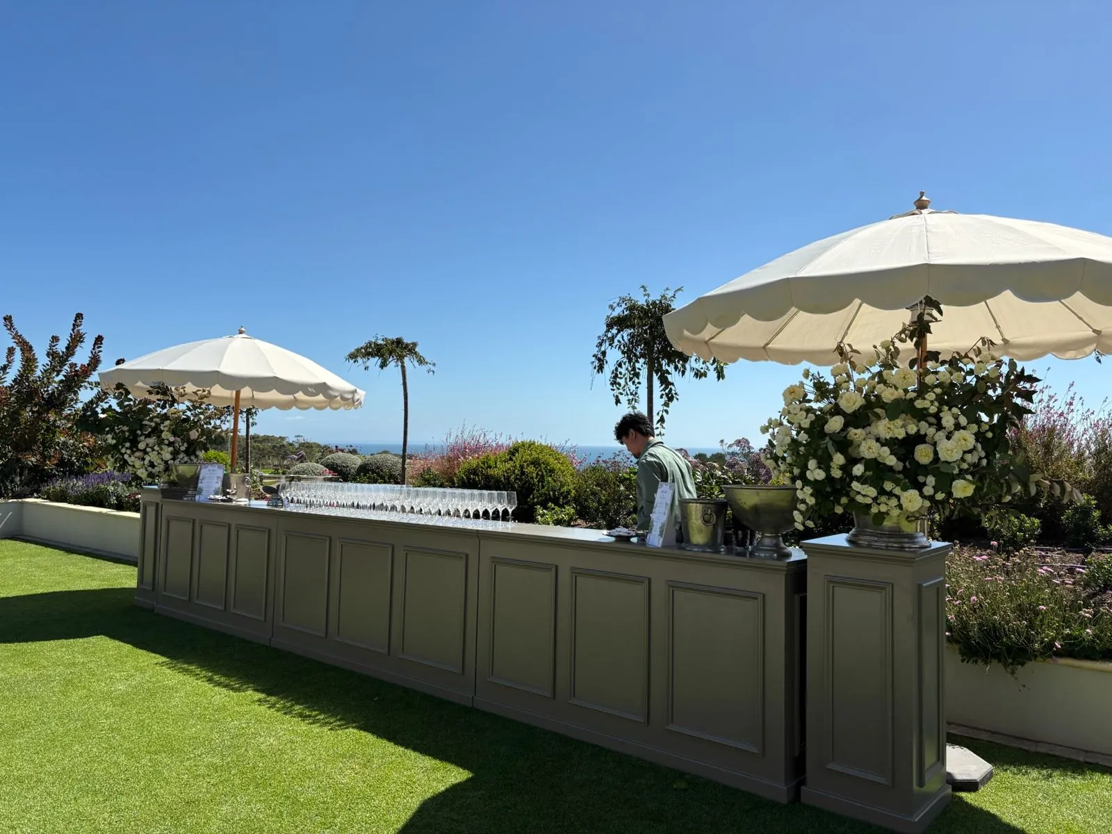 Outdoor wedding bar with cream umbrellas and ocean view